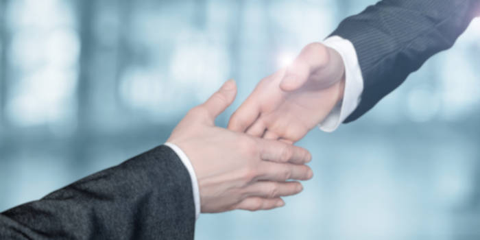 Close up photo of two businessmen reaching for a handshake